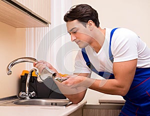 Young repairman working at the kitchen