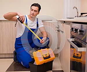 Young repairman working at the kitchen