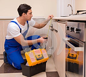 Young repairman working at the kitchen