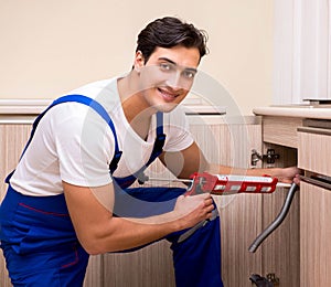 Young repairman working at the kitchen