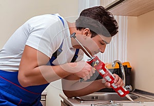 Young repairman working at the kitchen