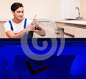 Young repairman working at the kitchen