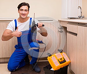 Young repairman working at the kitchen