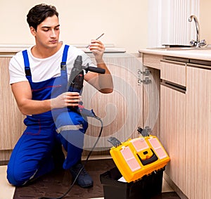 Young repairman working at the kitchen