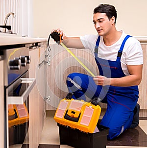 Young repairman working at the kitchen