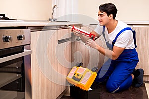 The young repairman working at the kitchen