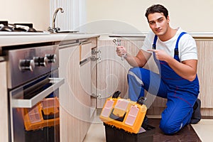 The young repairman working at the kitchen