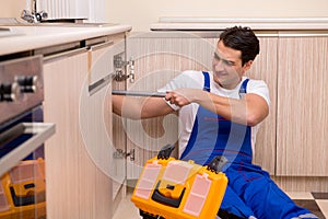 The young repairman working at the kitchen