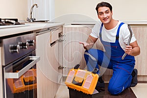 The young repairman working at the kitchen