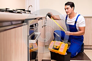 The young repairman working at the kitchen