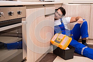 The young repairman working at the kitchen