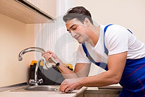The young repairman working at the kitchen