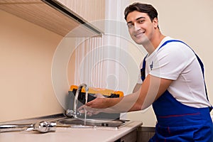 The young repairman working at the kitchen