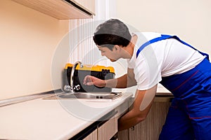 The young repairman working at the kitchen