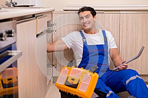 The young repairman working at the kitchen