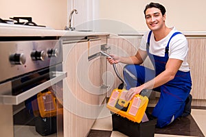 The young repairman working at the kitchen