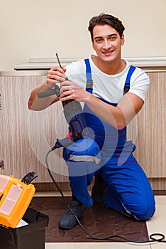 The young repairman working at the kitchen