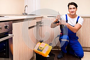 The young repairman working at the kitchen