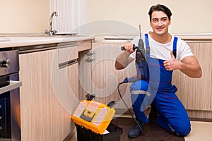 The young repairman working at the kitchen