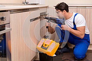 The young repairman working at the kitchen