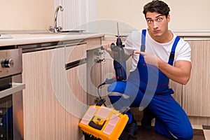 The young repairman working at the kitchen