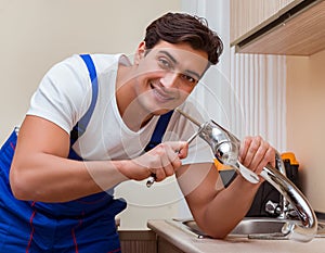 Young repairman working at the kitchen