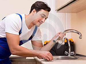 Young repairman working at the kitchen