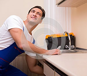 Young repairman working at the kitchen