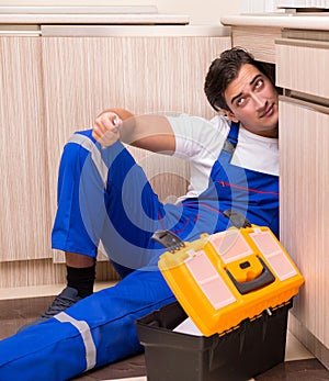 Young repairman working at the kitchen