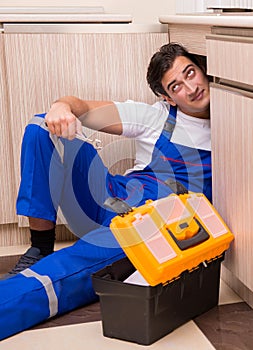 Young repairman working at the kitchen