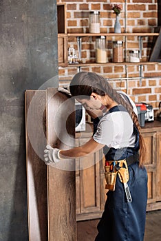 young repairwoman working with floor laminate