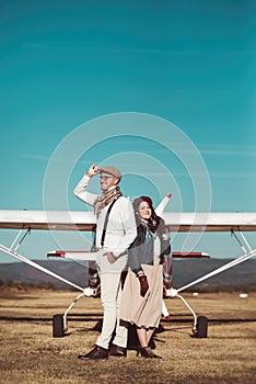 Young retro fashion couple posing in front of small plane