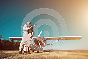 Young retro fashion couple posing in front of small plane