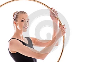 Young rhythmic gymnast exercising with hoop and looking at camera