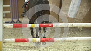 Young rider on black horse galloping at show jumping competition