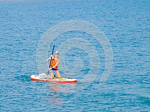 A young rider on a board for Sap surfing rakes a wave with a paddle, the concept of an active lifestyle