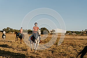 young rider dressed in a red shirt rides together with schoolmates on a white horse