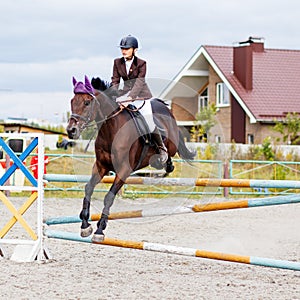 Young rider girl on horse show jumping competition