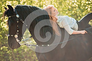 Young rider girl with long hair lying on horse neck