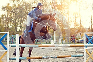 Young rider girl at show jumping. Jump hurdle