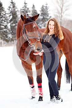 Young rider girl stand with horse in winter park