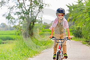 Young rider kid in helmet and sunglasses riding bicycle