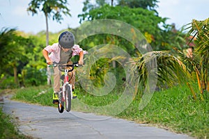 Young rider kid in helmet and sunglasses riding bicycle