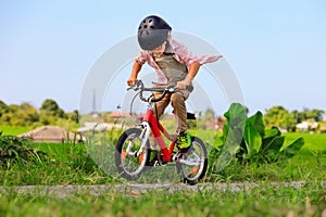 Young rider kid in helmet and sunglasses riding bicycle