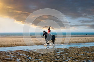 Beautiful young girl riding a Friesian mare on the coast of Hauts-de-France photo