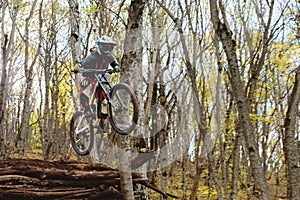 A young rider at the wheel of his mountain bike makes a trick in jumping on the springboard of the downhill mountain