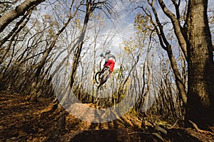 A young rider at the wheel of his mountain bike makes a trick in jumping on the springboard of the downhill mountain