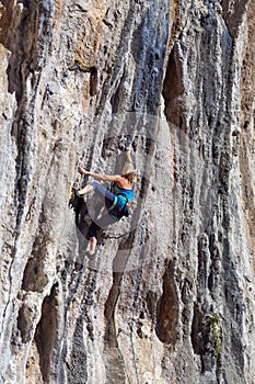 Young Rock Climber ascending steep colorful rocky Wall Lead Climbing