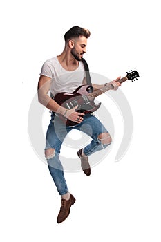 Young rock star jumping while playing during a concert