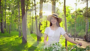 Young romantic beautiful woman with hat and white dress with retro vintage bicycle in sunset forest